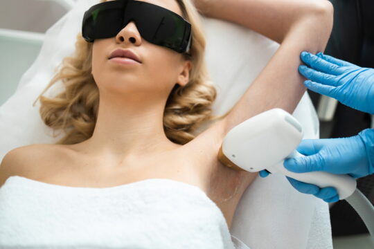 Underarm laser epilation. Beautician removing hair of young woman’s armpit. Smooth skin concept